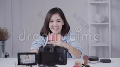 快乐微笑的亚洲女人或美女博主用画笔和相机录制视频，并在家挥手。